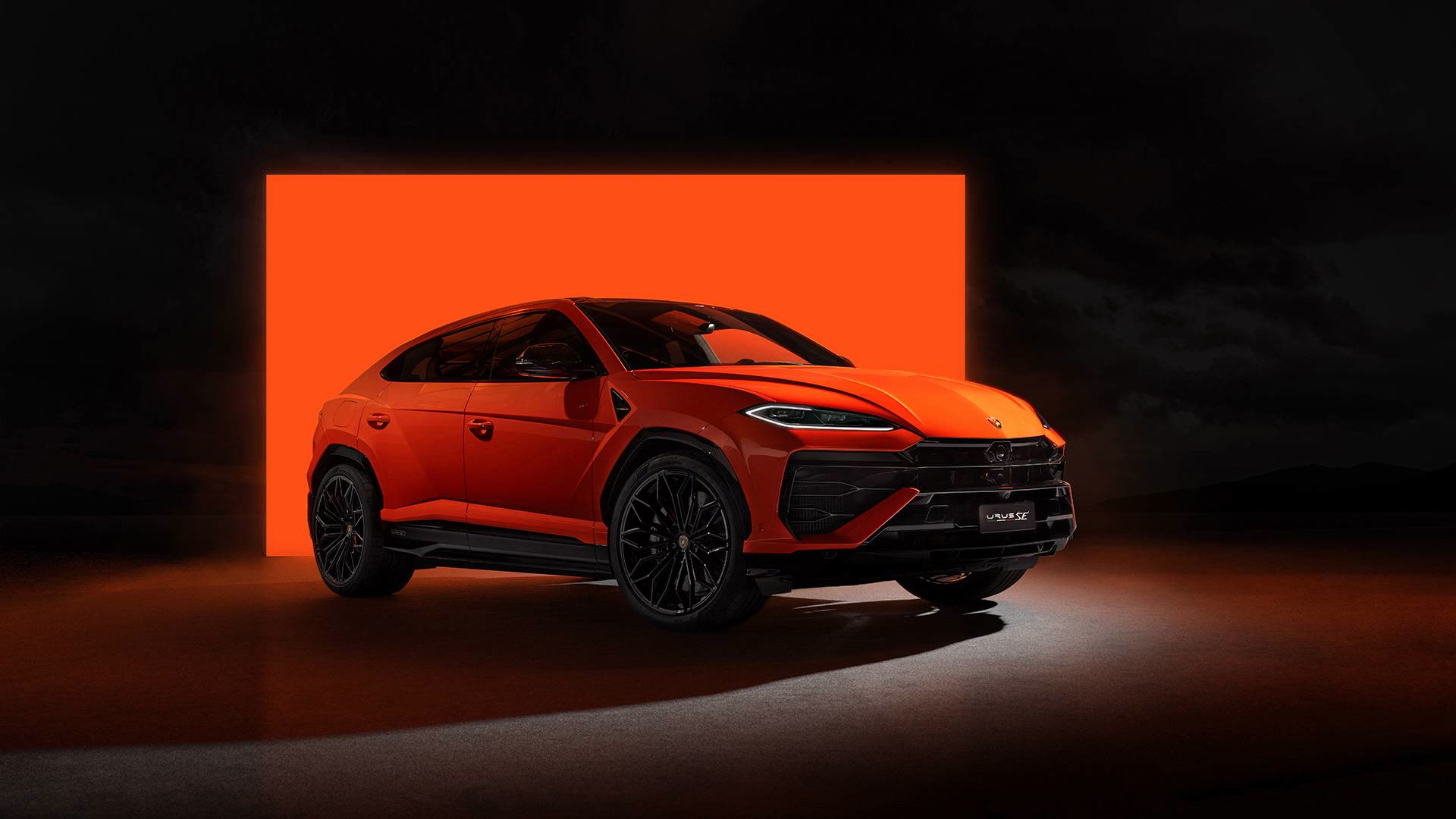 SUV sport orange devant un mur de lumière orange.