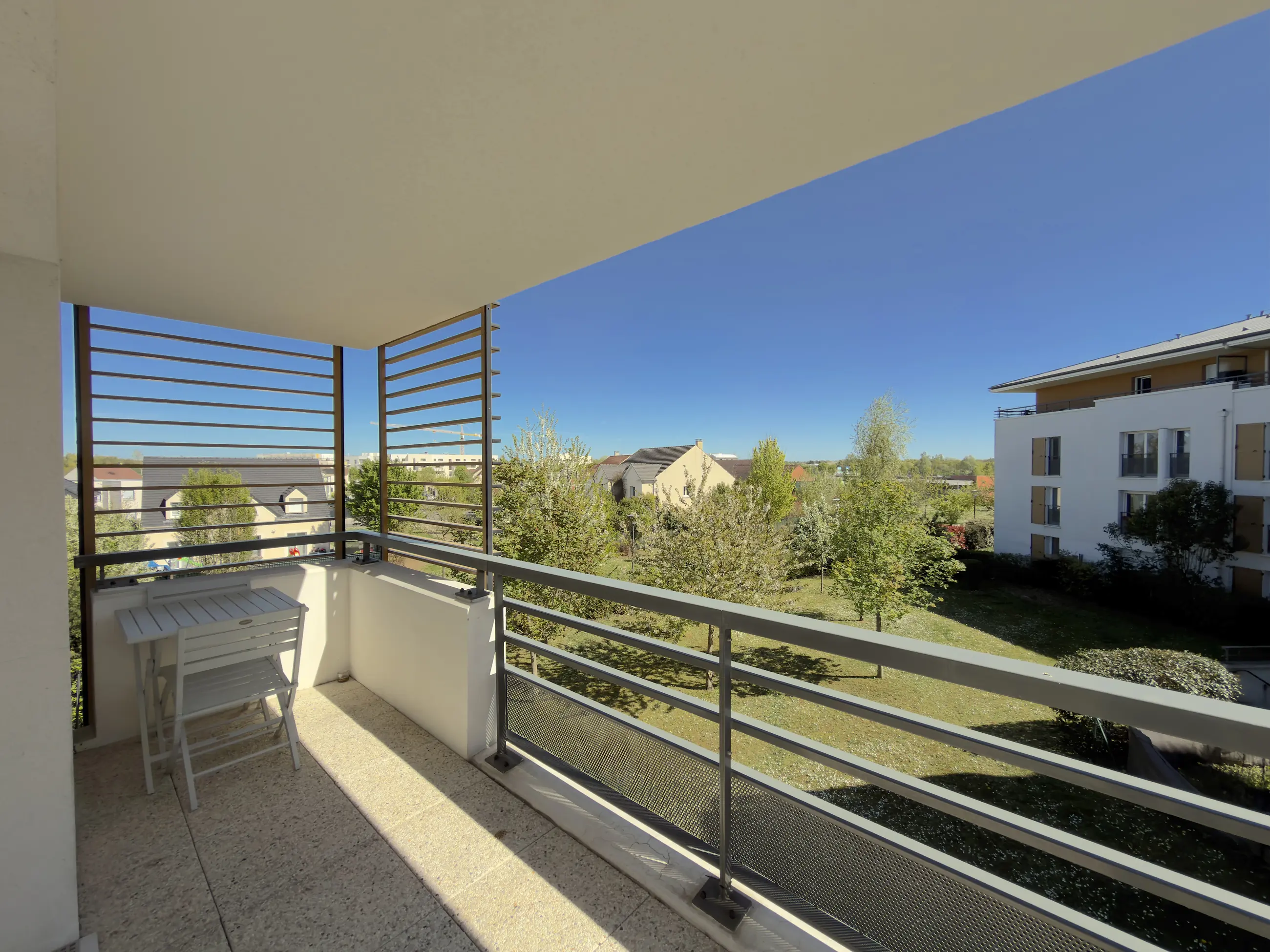 La vue depuis le balcon : les arbres de la résidence et le ciel.